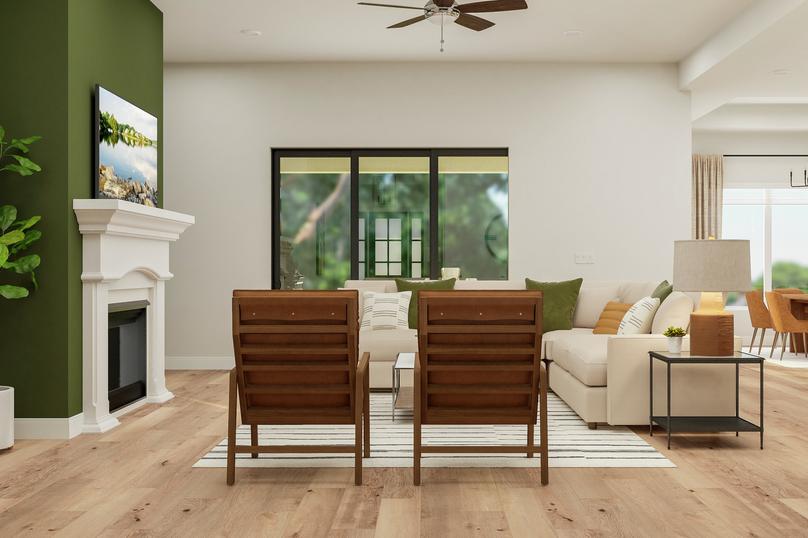 Rendering of the open floor plan living
  area furnished with large sectional couch, two armchairs, coffee table and  end table. A fireplace and sliding glass door complete the space while the  dining area is also visible.