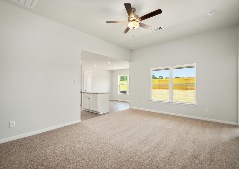The spacious family room has carpet and a ceiling fan. 