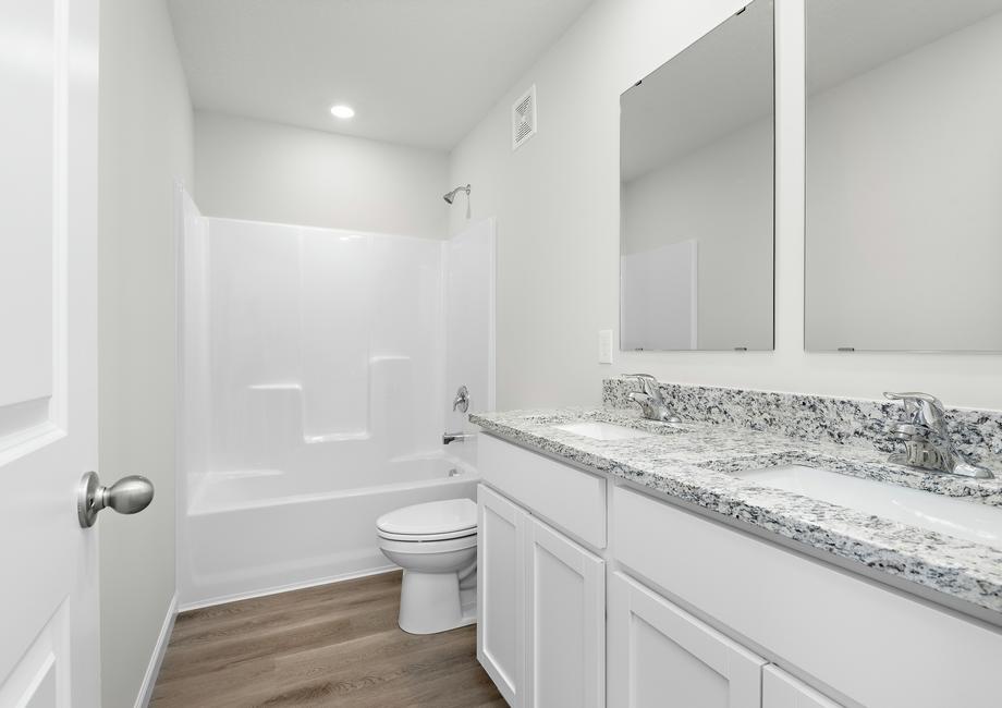 The secondary bathroom has a dual sink vanity and tub/shower combo.