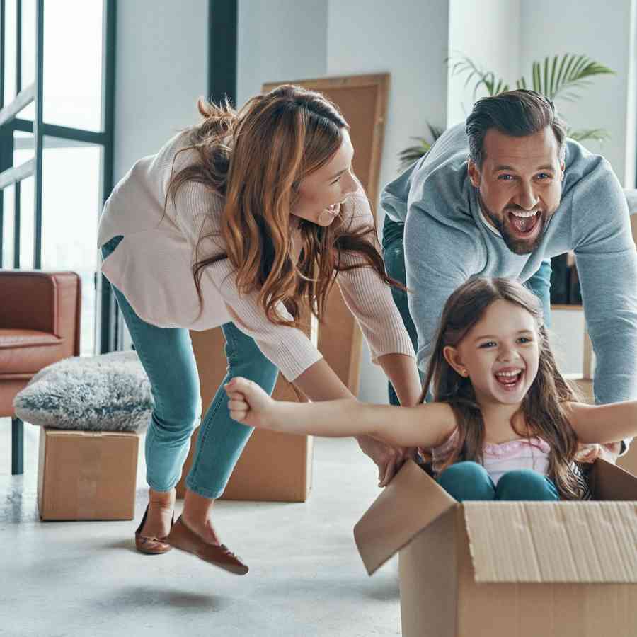 Stock photo of a cheerful young family smiling and unboxing their stuff while moving into a new home.