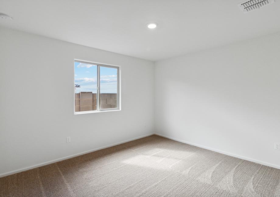 Guest bedroom with windows, tan carpet and recessed lighting.