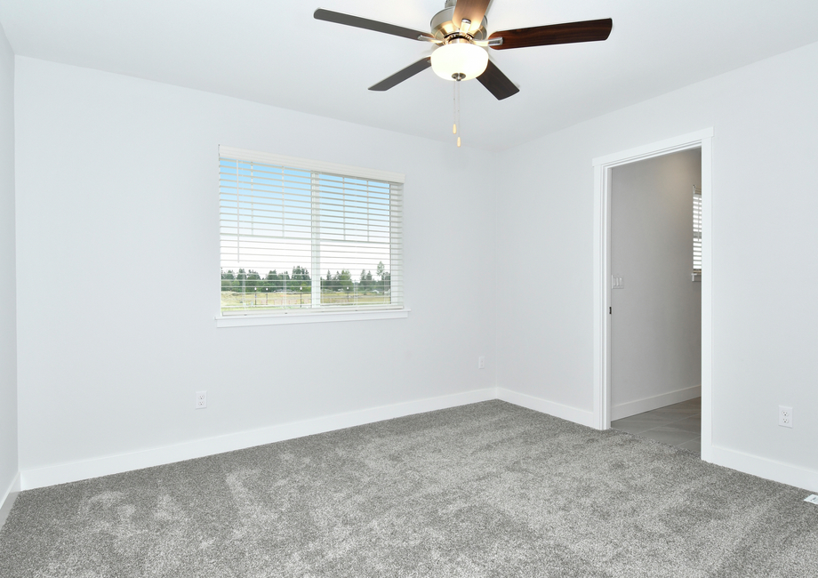 The master bedroom is spacious with a ceiling fan.