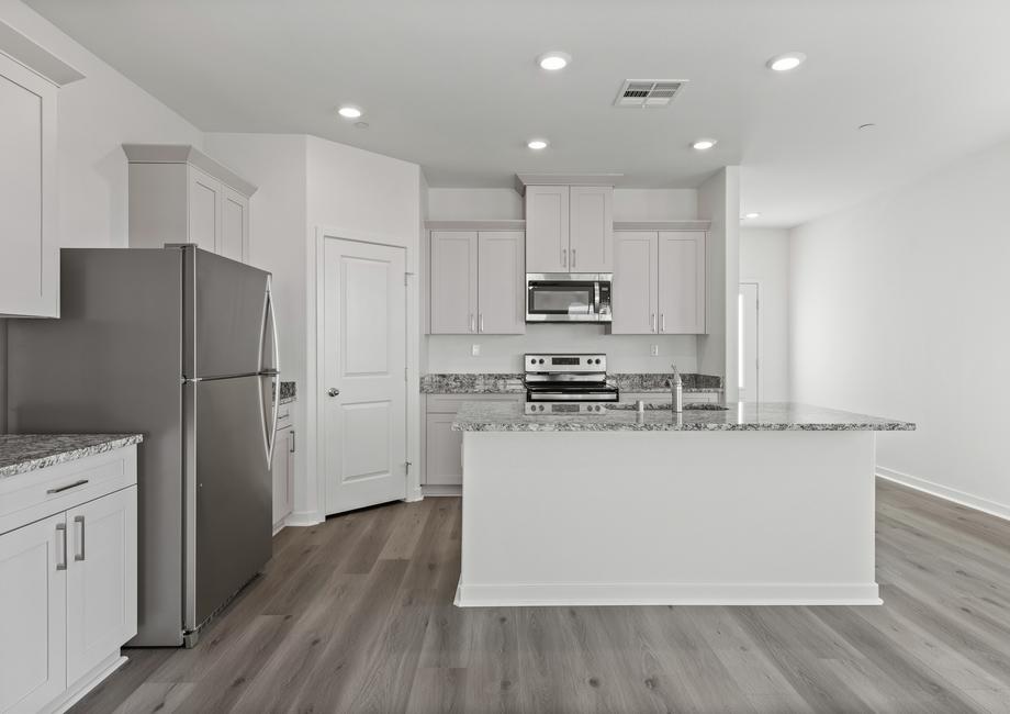 The kitchen has plank flooring and stainless steel appliances.