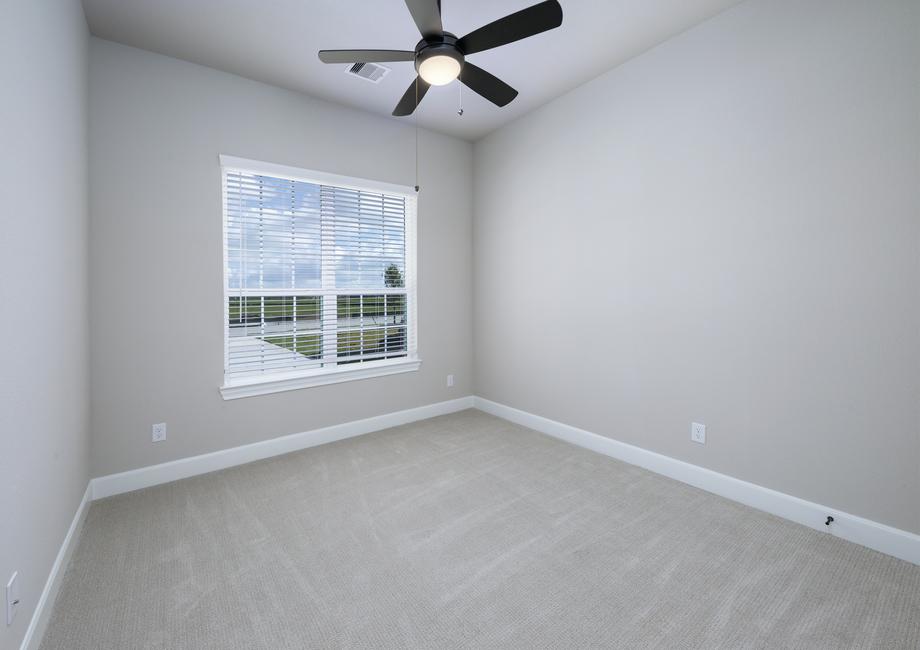 Secondary bedroom with carpet, a ceiling fan and a window.