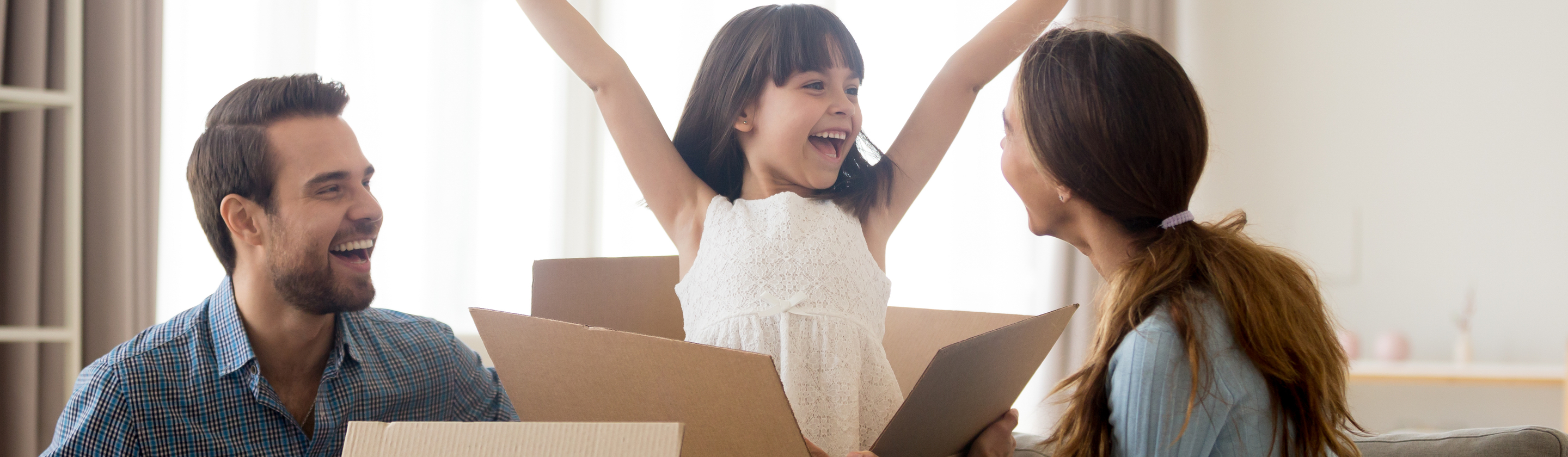Family unpacking boxes, happy girl with arms in air