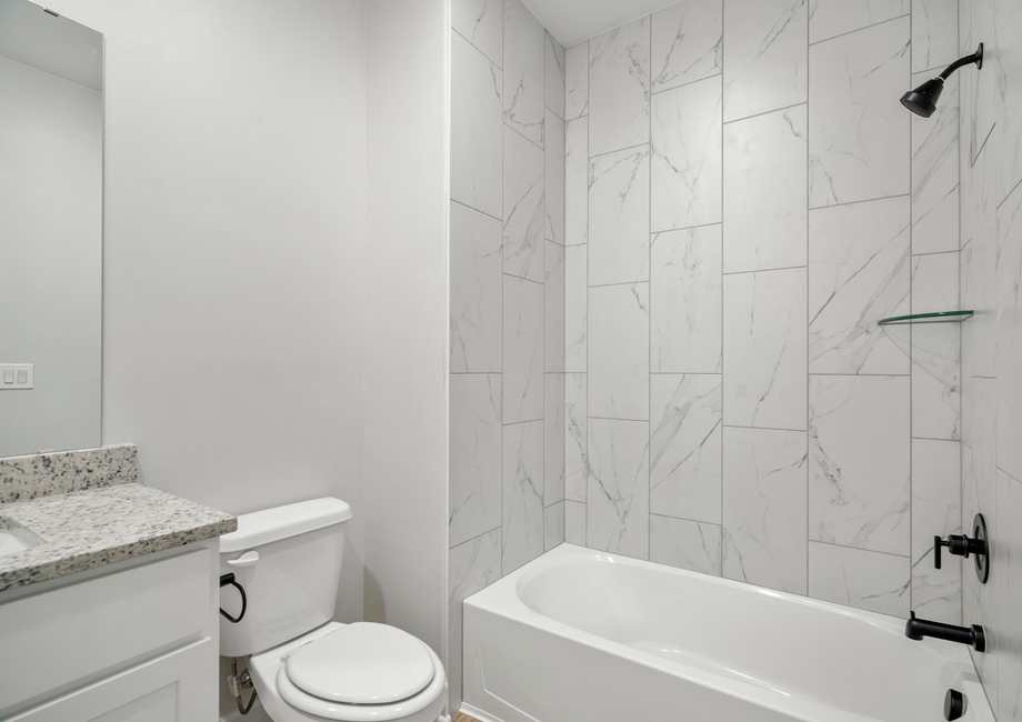 The secondary bathroom has a beautiful tiled shower-tub combo.