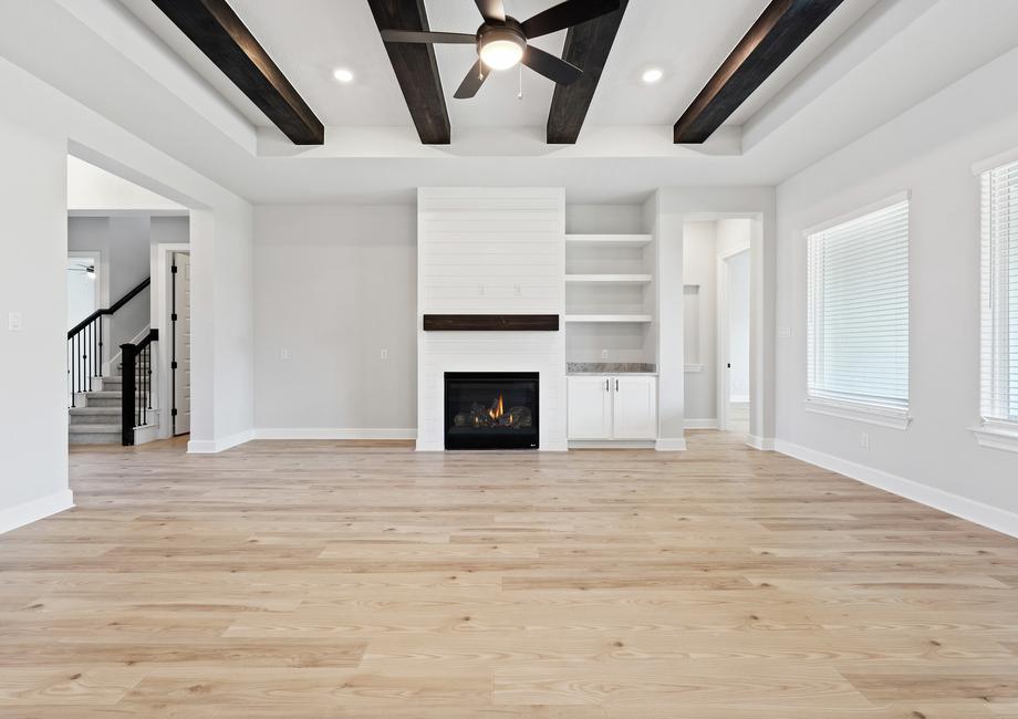 Spacious living room with beam accents and a fireplace with shiplap siding accents.