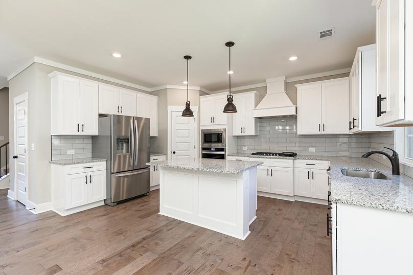 Kitchen with granite countertops, stainless appliances and pendent lights.