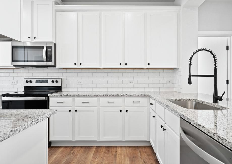 Stunning white cabinetry featuring black hardware and marble countertops.