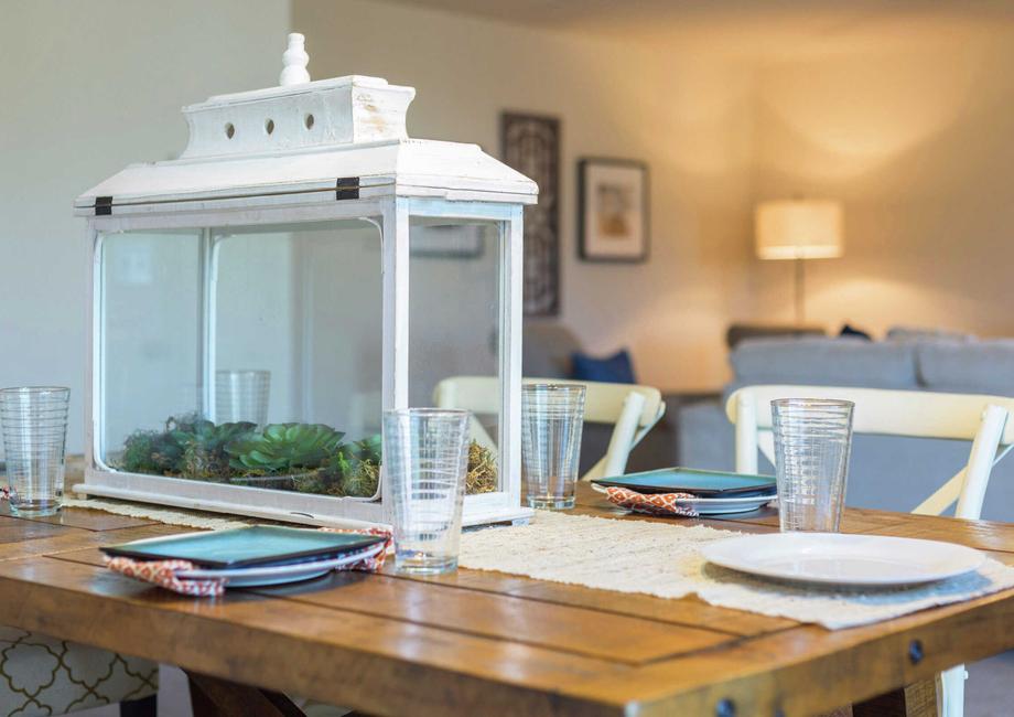 Home with wooden dining table that has place settings, tablecloth and a white decorative box on top.