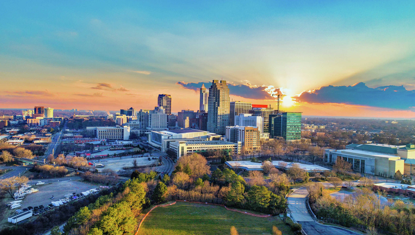 Raleigh, North Carolina downtown cityscape with large office buildings, parks, and other buildings at sunrise