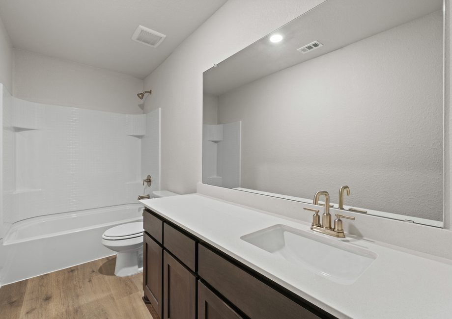 The secondary bathroom has a large vanity space and a shower-tub combo.