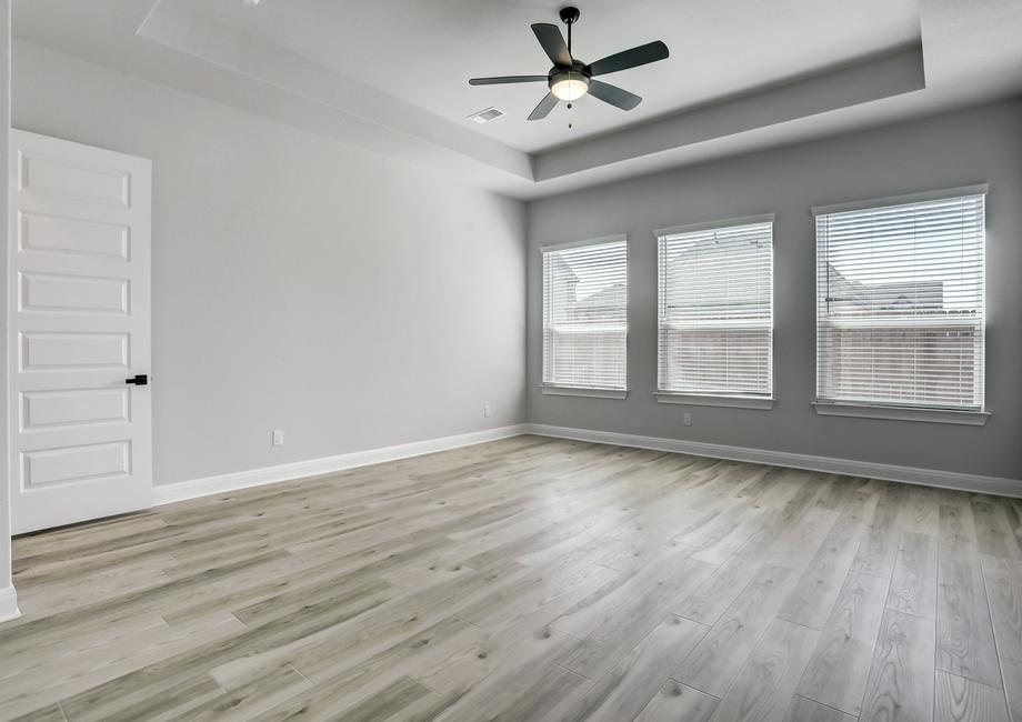 Expansive master bedroom with three large windows, creating a bright and open space.
