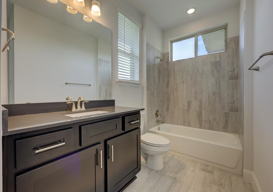 Secondary bathroom with a tile-lined dual shower and tub to meet the needs of your household.