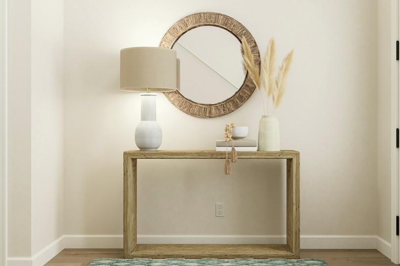 Rendering of the entryway showing the 3/4
  lite front door. The space is furnished with a console table, rug and round
  mirror.
