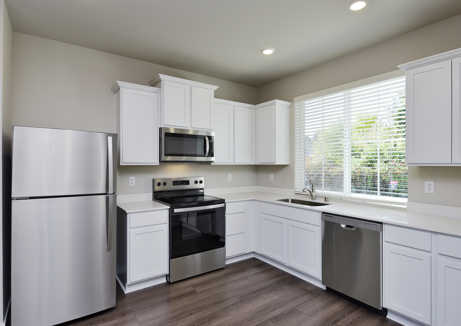 The kitchen has stainless steel appliances and plank flooring.