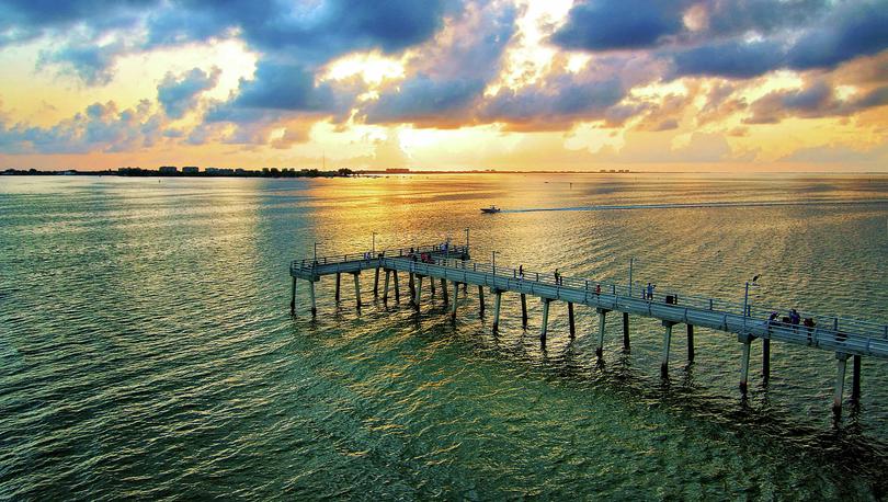 Sarasota, Florida Bay pier from the Ringling Bridge at sunrise with cloudy skies and dark waters