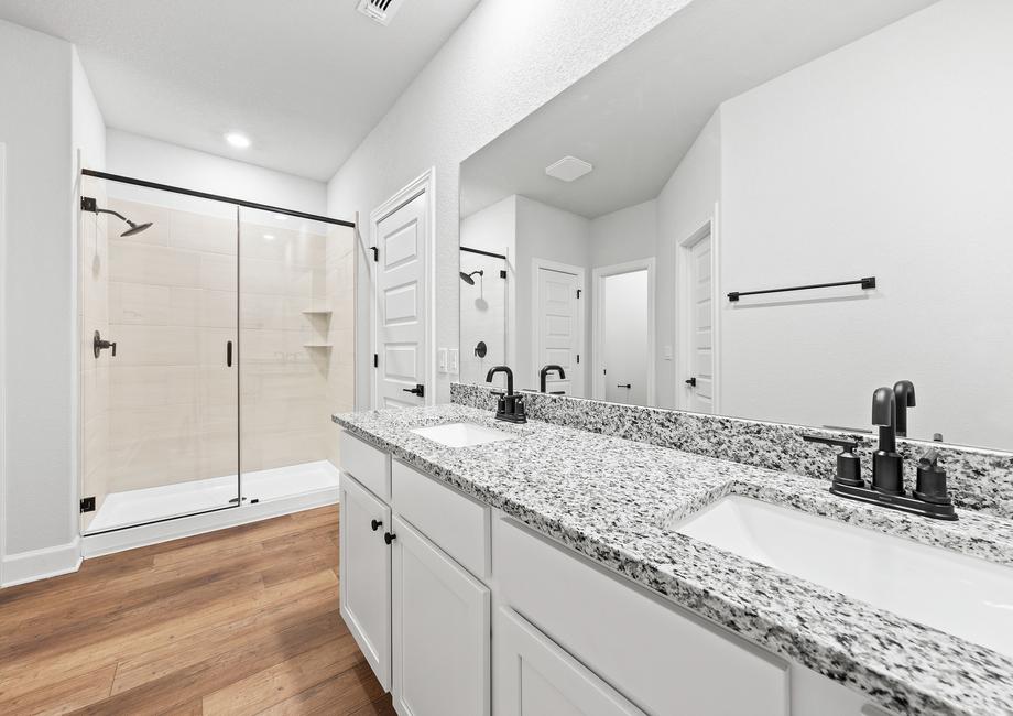 Serene master bathroom featuring the upgraded dual sink vanity and  the beautifully tiled walk-in shower.