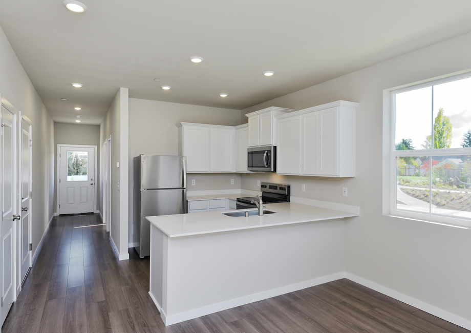 The kitchen has stainless steel appliances and plank flooring.