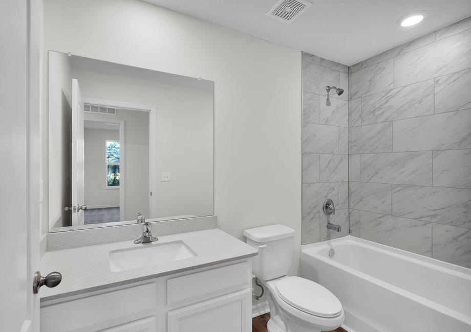 The secondary bathroom has a stunning vanity and a soaker tub.