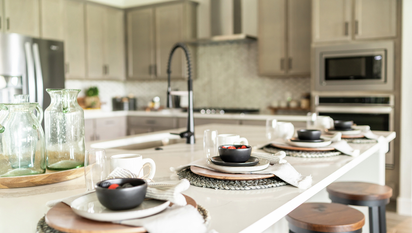 Kitchen with quartz countertops, grey cabinets and stainless steel appliances.