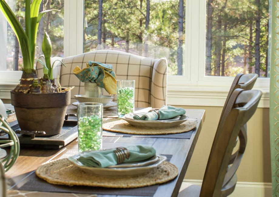 Dining nook with large window, chandelier and a kitchen table.