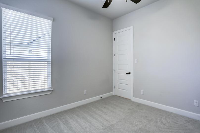 Secondary bedroom with plush carpet and a ceiling fan.