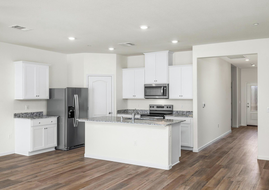 The kitchen has stainless steel kitchen appliances and plank flooring.