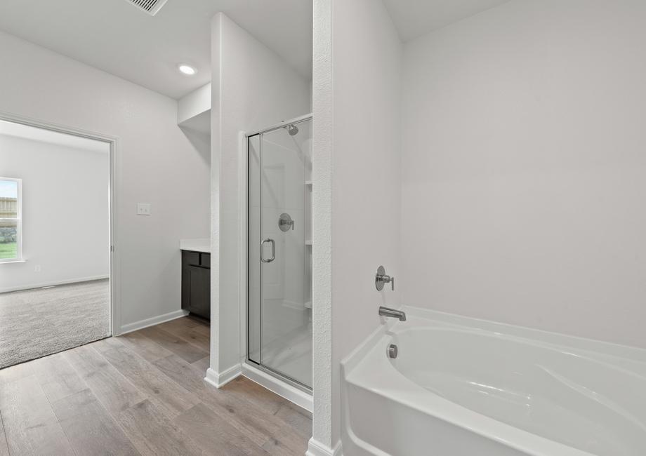 The master bathroom of the Driftwood plan has a glass walk-in shower and large garden tub.