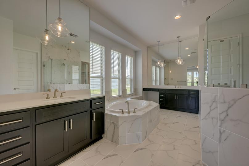 Stunning, spa-like master bath that features two vanity areas, a soaking tub, and walk-in shower.