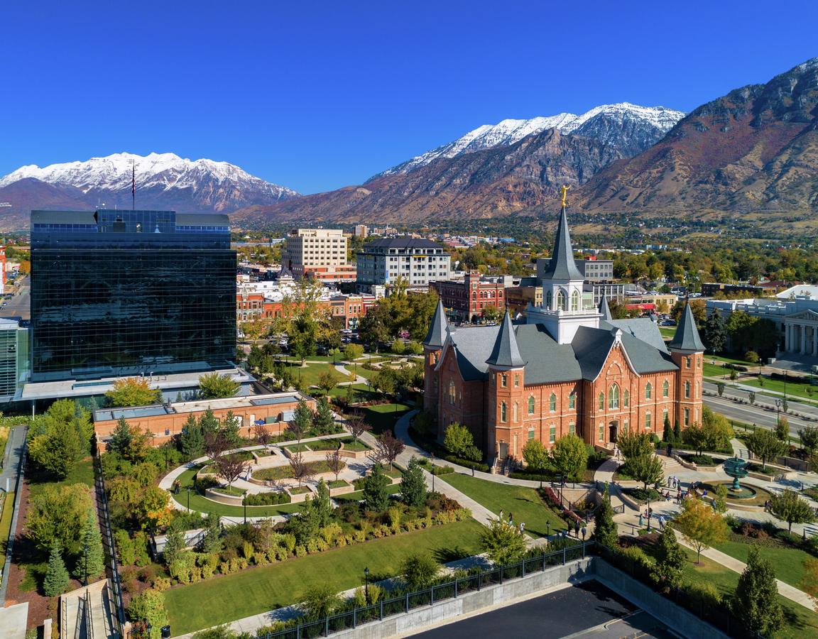 Aerial of downtown Provo, Utah showing the Provo City Center Temple and One Nu Skin Plaza, with the snow capped Wasatch Mountain Range in the background.