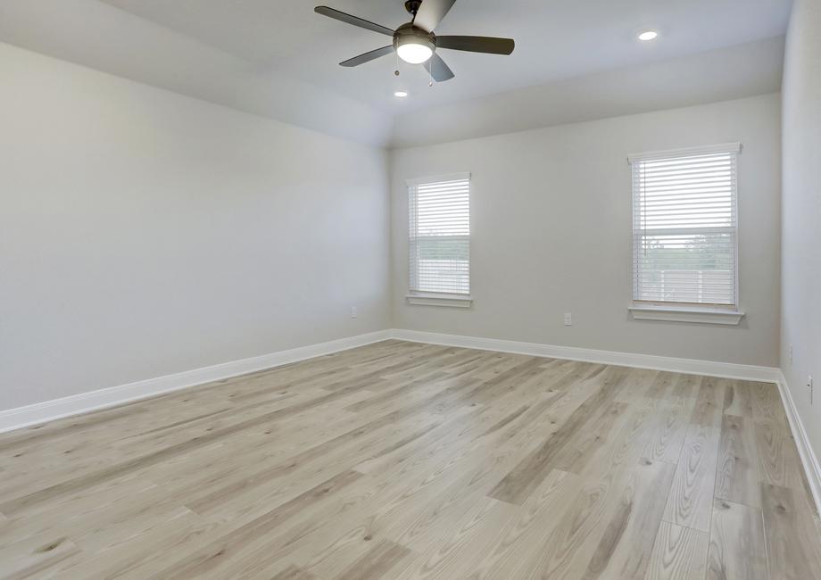 Spacious master bedroom with a ceiling fan and two large windows.
