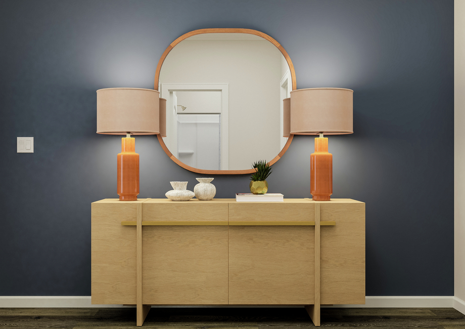 Rendering of the entryway with vinyl  plank wood flooring. The wall has been painted a dark blue and the space is  furnished with a decorative storage cabinet, two lamps and a large mirror.