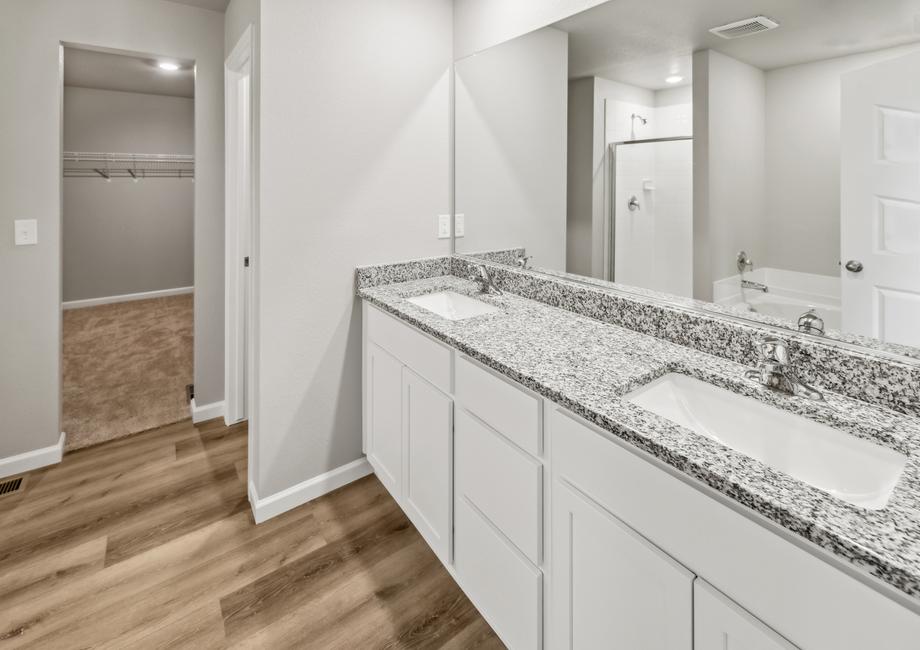 The master bathroom also boasts white cabinets, a double-sink vanity, and walk-in closet.