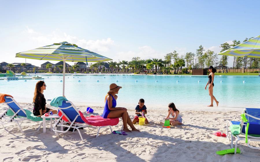 People sitting by a lagoon on sand.