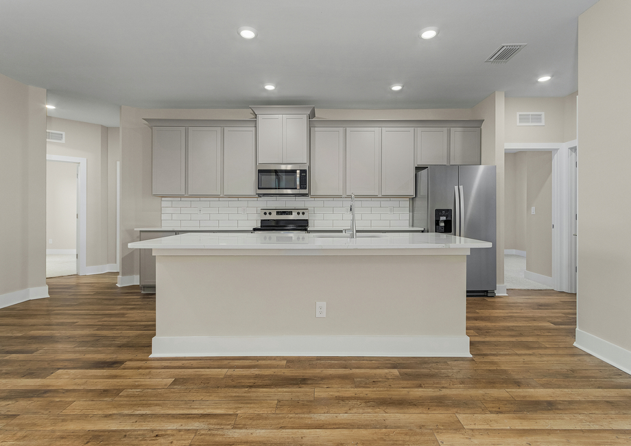 Spacious kitchen with gray cabinets, large island and white subway tile backsplash.