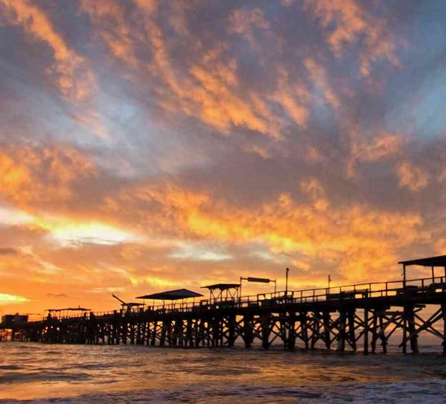 Tampa, Florida Redington Beach at sunset with silhouette of pier and rolling waves coming in