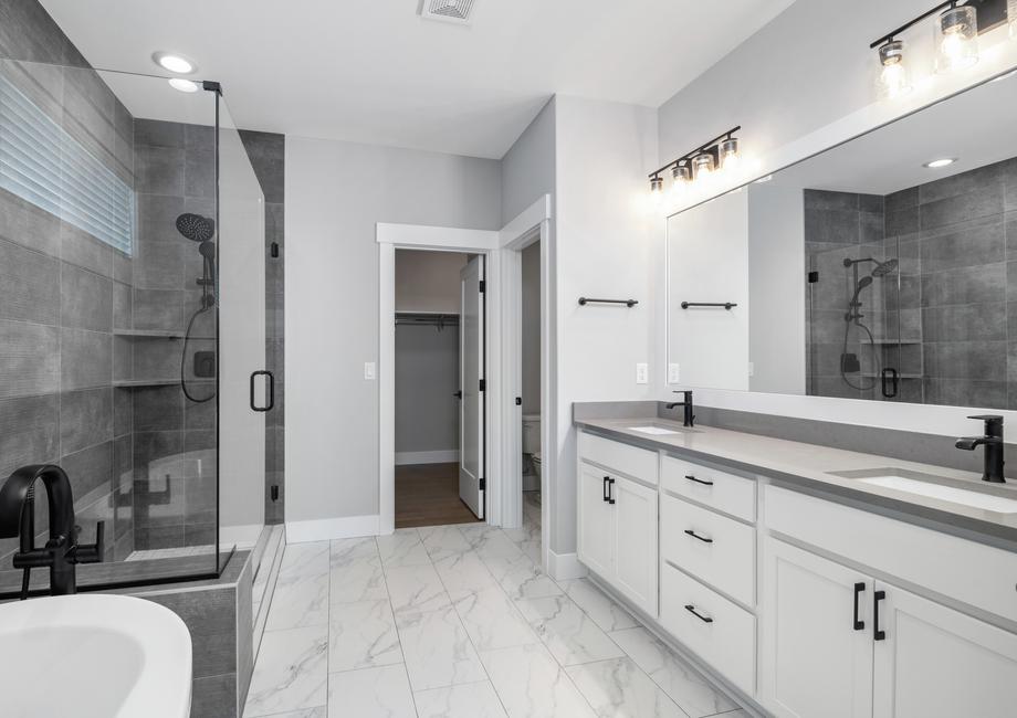 The master bathroom showcases an impressive glass encased shower and a relaxing standalone tub.
