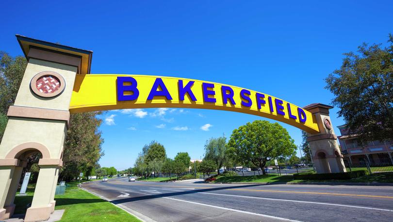 Bakersfield, California welcome sign with the word Bakersfield in blue on a yellow backdrop and spanning across a multi-lane street