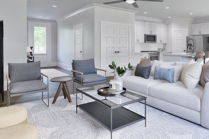Modern open-concept family room with a large light gray sectional, accent chairs, ceiling fan, and view of kitchen and dining area.