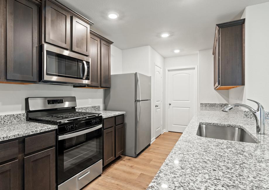 The kitchen of the Cedar has beautiful wood cabinetry and sprawling granite countertops.