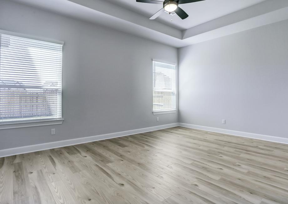 Spacious master bedroom with large windows and a ceiling fan create a peaceful retreat.