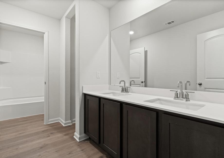 The secondary bathroom of the Driftwood has a large dual-sink vanity and shower-tub combo.