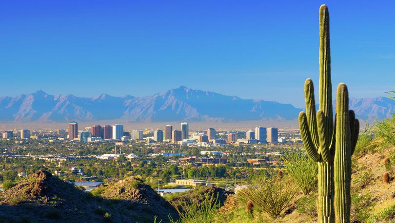 Phoenix, Arizona skyline with saguaro cacti, city skyscrapers, and South Mountain in the background