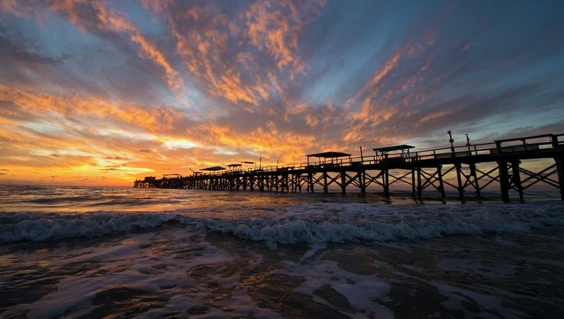 Tampa, Florida Redington Beach at sunset with silhouette of pier and rolling waves coming in