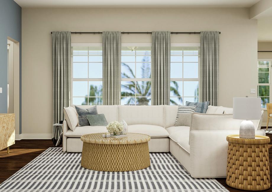 Rendering of living room showing a beige
  media cabinet and tv on left, a white sectional couch and coffee table in
  front of large windows center, and the corner of the dining room on right
  with dark wood look flooring throughout.