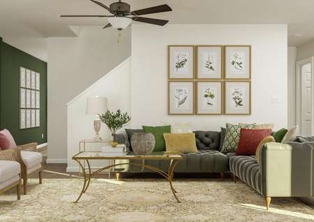 Rendering of the living room looking
  towards the stairs. The space is furnished with a sectional couch, two
  armchairs, a coffee table and end table.