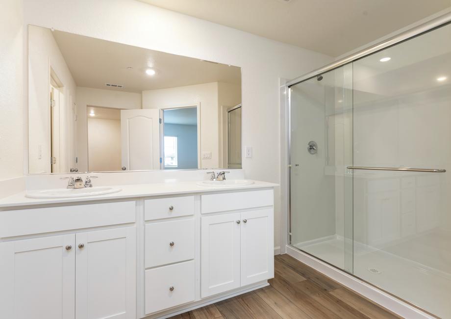 The master bathroom has a dual sink vanity and a step in shower.