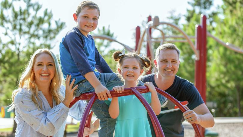 Smiling family of four on a children's playground. 