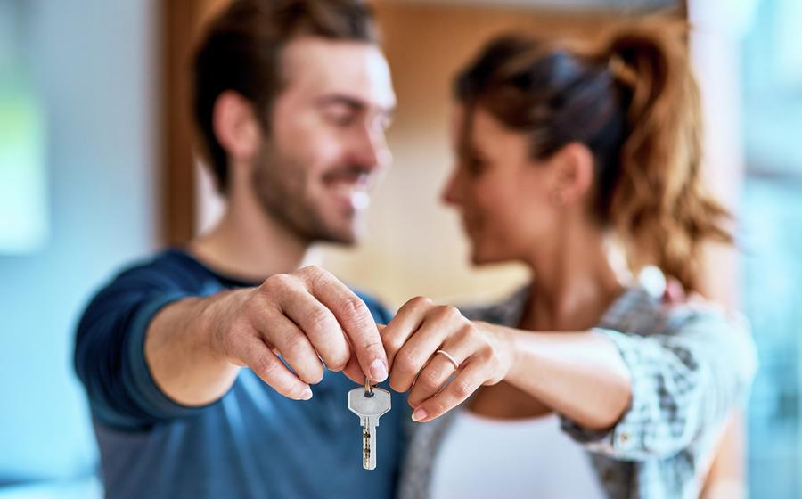 Couple holding up keys to their new home.